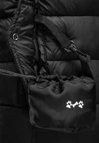 Black puffer jacket featuring a secured pocket with paw print design. Smooth texture with quilted pattern and adjustable strap detail.