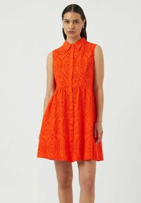 Oranssi hihaton mekko, jossa on kauluksellinen pääntie, nappikiinnitys edessä, rei'itetty kuvio ja kerrostettu vyötärö A-linjaiselle siluetille.