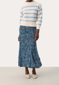 Blue and cream striped sweater with a ribbed texture, paired with a blue floral-patterned maxi skirt. Model is wearing light-colored shoes.