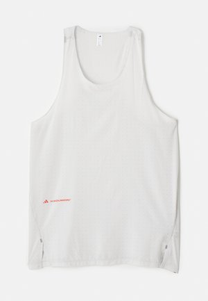 Débardeur blanc sans manches en tissu léger, avec des petits motifs en points et des fentes sur les côtés. Logo de la marque en rouge en bas à gauche.