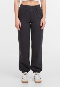 Zwarte sweatpants met een elastische tailleband en gathered cuffs, gemaakt van zacht materiaal. Draag het met beige sneakers.
