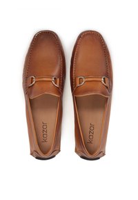 Mocasines de cuero marrón con detalles de hardware plateado. Textura suave y diseño de punta redonda. Nombre de la marca 'kazar' visible en la plantilla.