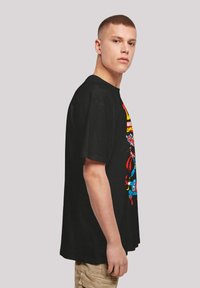 Black cotton t-shirt featuring colorful comic book character graphics on the front. Short sleeves and relaxed fit design.