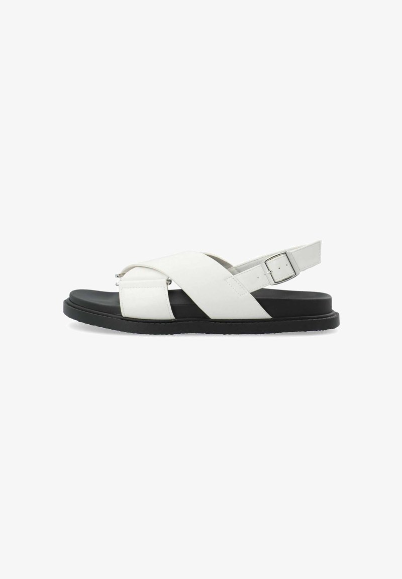 Witte lederen sandalen met een kruisbandontwerp, voorzien van een zwarte zool en een verstelbare enkelgesp. Gladde textuur, minimalistische stijl.