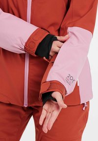 Rode en roze skijas met een klittenbandsluiting op de pols, zwarte binnenvoering en een rits. Bevat een logo met "20K" gedrukt op de mouw.