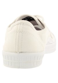 Białe płócienne trampki o teksturowanej powierzchni, gumowej podeszwie i zaokrąglonym tyle. Wewnątrz buta widoczne sznurowadła oraz metka z logo.