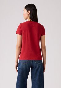 Rød bomull t-skjorte med korte ermer og rund hals, kombinert med høyt liv blå denimjeans med en klassisk baklomme-design.