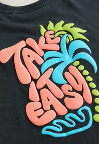 Black fabric with a prominent design featuring the text "TAKE IT EASY" in pink and blue, alongside green palm leaves and wave accents.