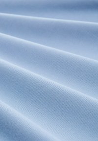 Tissu bleu clair avec une surface lisse et texturée, présentant un léger nervuré et des plis, mettant en valeur sa douceur et sa flexibilité.