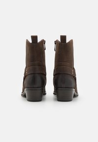 Hnědé kotníkové boty s kombinací hladkého a semišového povrchu, kulatou špičkou, bočními zipy a designem s podpatkem.