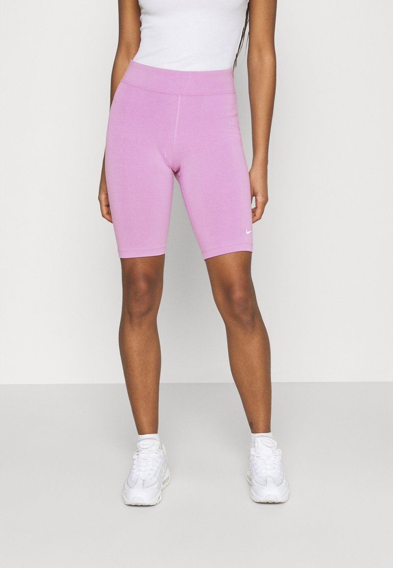 Vaaleanpunaiset pyöräilyshortsit, jotka on valmistettu joustavasta kankaasta, ja niissä on sileä pinta sekä korkea vyötärö. Vasemmassa reidessä on näkyvä pieni valkoinen logo.