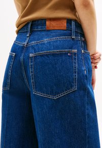 Jeans od trapera tamno plave boje s opuštenim krojem, s kontrastnim šavovima, stražnjim džepovima i smešnim kožnim etiketom s logom.