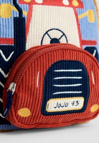 Röd och blå kordflöjelsryggsäck med en broderad traktordesign, i texturerat tyg, en dragkedjeficka och flerfärgade detaljer.