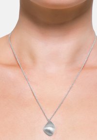 Collana d'argento con un pendente a forma di foglia, texture rilievo e dettagli a coste, appesa a una sottile e delicata catena.