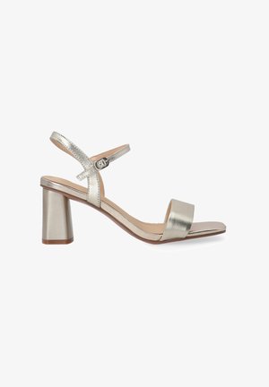 Metallic sølvhælede sandaler med bred forreste rem, justerbar ankelrem og blokhælhæl. Glat tekstur, minimalistisk design.