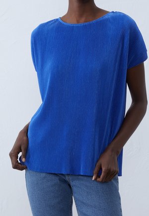 Haut bleu à manches courtes en côtes avec un col rond, coupe décontractée et tissu texturé, assorti à un jean bleu clair.