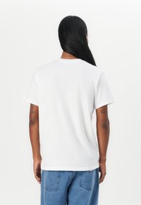 Tricou alb cu maneci scurte si decolteu rotund. Material din bumbac, croi lejer, si design simplu, fara modele sau grafica vizibile.