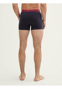 Boxer noirs avec une large ceinture bordeaux arborant le logo « TOM TAILOR ». Le matériau semble lisse avec un design ajusté.