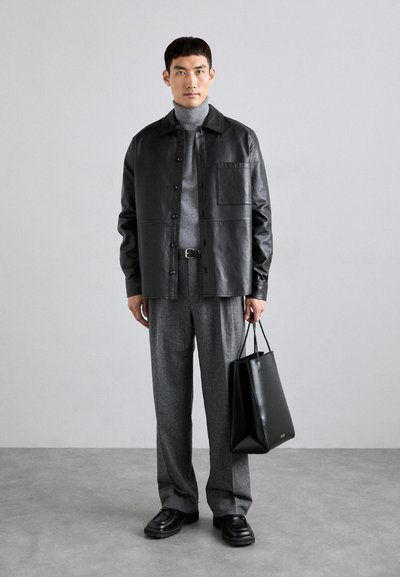 Svart läder skinnjacka med framficka, grå polotröja, grå byxor och svart axelväska. Svarta skor med kraftig sula.