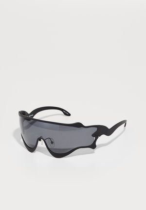 Des lunettes de soleil noires au design audacieux et sculptural avec des verres teintés foncés. Elles présentent une monture légère et des bords courbés distinctifs.