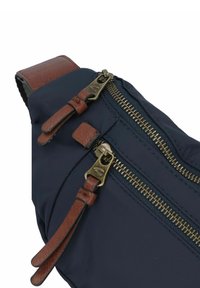 Navyblauwe schoudertas met twee messing ritsen met leren trekkoordjes, aangevuld met bruine leren accenten op de schouderband.