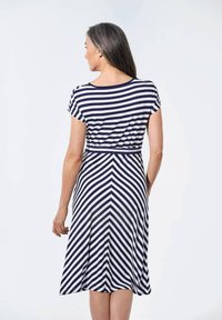 Marineblau und weiß gestreiftes Kleid mit kurzen Ärmeln, tailliertem Oberteil und ausgestelltem Rock, der auf der Rückseite und an der Taillenpartie mit Zickzackmustern verziert ist.