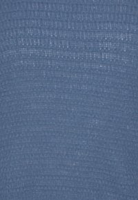 Texturerad blått tyg med ett vävt mönster, som uppvisar en lätt ribbad yta. Materialet verkar mjukt och flexibelt.