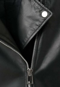 Zwarte leren jas met een zilveren ritssluiting, voorzien van een notched kraag en zichtbare stikdetails. Het interieur is glad en niet gevoerd.