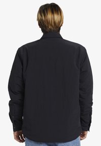 Schwarzes langärmliges Hemd mit einem kragenförmigen Design, strukturierter Silhouette, geknöpften Manschetten und einem glatten, strukturierten Stoff.