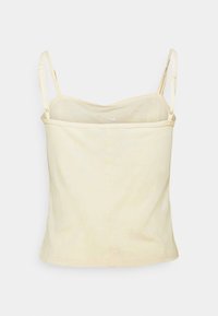 Ljusgul tanktop med tunna axelband, rundad utskärning och mjuk bomullstextur. Har en liten vit logotyp på framsidan.