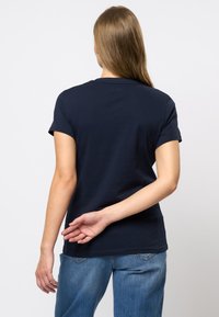 Mörkblå bomull t-shirt med kort ärm och rundad hals, visad bakifrån. Avslappnad passform med en jämn textur och minimala detaljer.