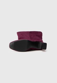 Botine din suede bordeux cu o talpă din cauciuc negru neted, având un vârf rotunjit și un design minimalist. Fără detalii hardware vizibile.