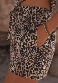 Szorty w panterkę z elastycznym pasem i wiązaniem, o gładkiej fakturze oraz bocznymi kieszeniami dla funkcjonalności.