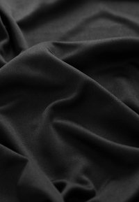 Tessuto nero con una texture liscia, caratterizzato da una leggera lucentezza e una caduta morbida. Il materiale presenta pieghe e curve delicate, creando profondità.