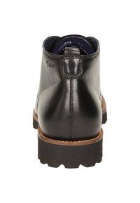 Bottine en cuir noir avec une texture lisse, bout rond et une semelle en caoutchouc marron contrastante. Équipée d'une languette à l'arrière pour un enfilage facile.