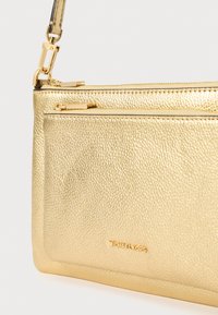 Borsa a mano in pelle dorata con superficie testurizzata, dotata di chiusura a zip, tracolla removibile e logo del brand impresso.