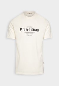 Cremfarbener Baumwoll-T-Shirt mit auffälligem schwarzen "CLUB Broken Heart" Grafiktext, Rundhalsausschnitt und kurzen Ärmeln sowie einem Etikett an der Seite.
