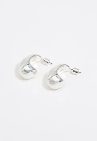 Orecchini a cerchio in argento con un design liscio e curvo. Finitura metallica lucida con una forma organica sottile e chiusura a farfalla.