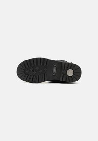 Semelle en caoutchouc noir avec des motifs de crampons prononcés et un motif en étoile. Comprend un logo de marque et une surface texturée pour une meilleure adhérence. Conception solide et durable.