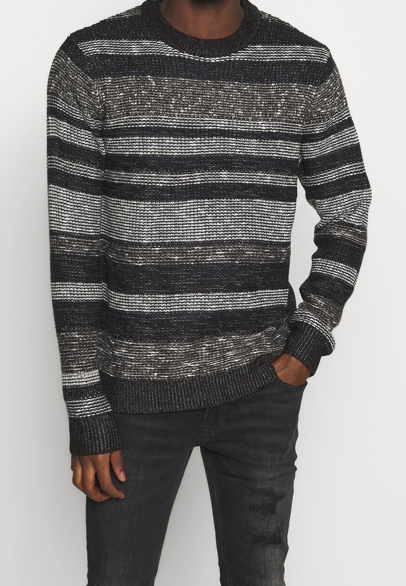 Handstickad tröja i svart och vitt med horisontella ränder. Har ribbade ärmslut och halsringning, med ett texturerat garn och en avslappnad passform.