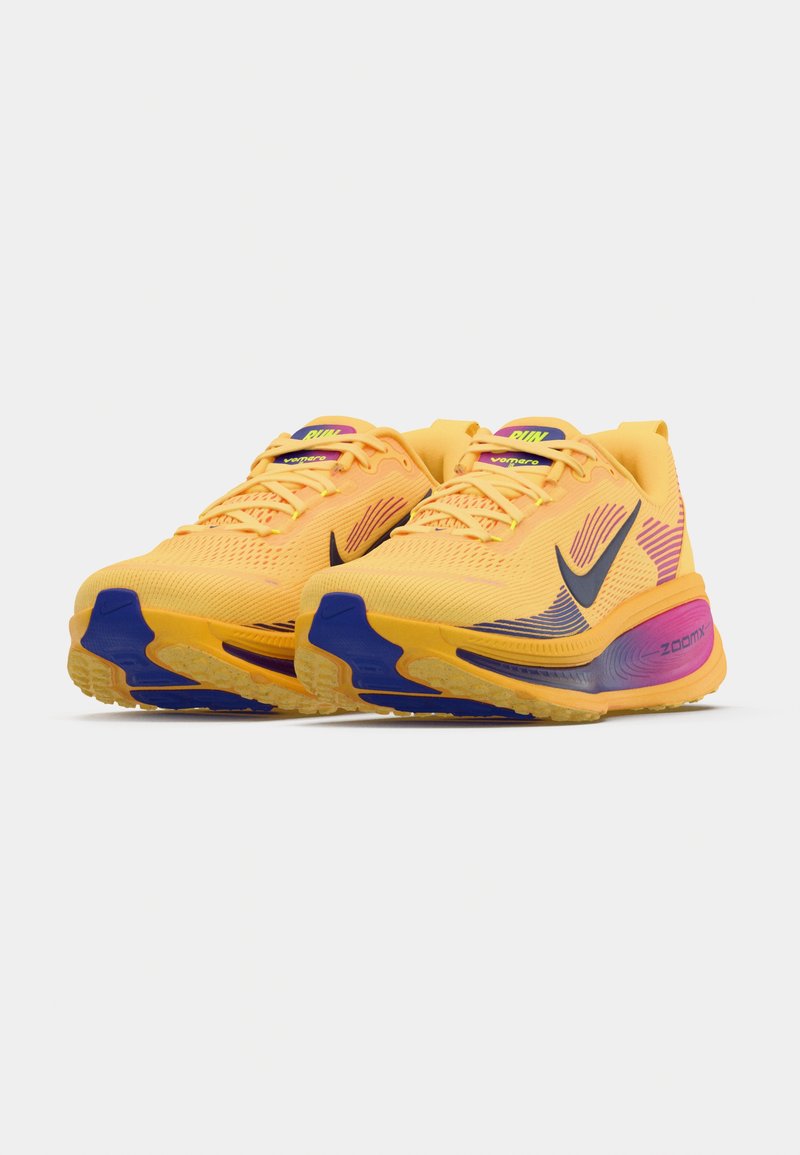 Zapatillas de running Nike ZoomX en amarillo con acentos multicolores. Parte superior de malla con patrón texturizado, logotipo negro y suela acolchada con detalles en azul.