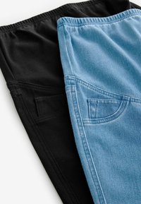 Zwarte en lichtblauwe broeken, met een elastische tailleband, een gladde textuur en voorzakken. De zwarte variant is effen, de blauwe heeft een denimlook.