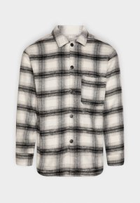 Chemise en flanelle à carreaux noir et blanc avec col, fermeture à boutons et une poche poitrine. Texture douce et manches longues.