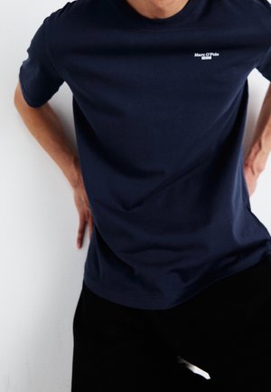 Navyblauwe katoenen t-shirt met korte mouwen en een ronde hals; beschikt over een klein wit logo op de linkerkant van de borst en heeft een gladde textuur met een minimaal design.