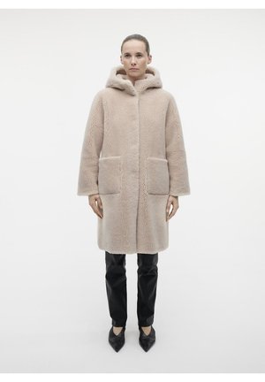 Beige nepbonten jas met een capuchon, met een rechte snit, twee voorzakken en een zachte textuur. Gecombineerd met zwarte broek en puntige schoenen.