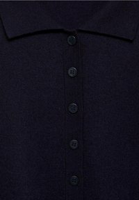 Námořnická modrá pletená polo košile s klasickým límcem a šesti černými knoflíky vpředu. Hladká textura s ribbeným materiálem.