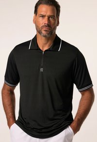 Polo shirt noir avec un col zippé, des manches courtes et des rayures blanches sur les poignets. Fabriqué en tissu lisse et léger.