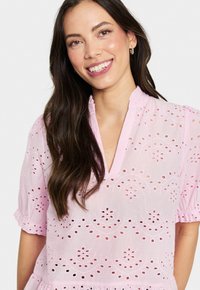 Rosa bestickte Bluse mit V-Ausschnitt, kurzen Puffärmel und dekorativen Ausschnitten im gesamten Stoff.
