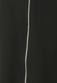 Tessuto nero con una texture liscia, caratterizzato da una cerniera argentata ben visibile lungo un lato. Il design è semplice e slanciato.