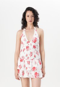 White halter dress with red and pink floral pattern, smocked bodice, and layered ruffle skirt. Lightweight fabric with a soft texture.